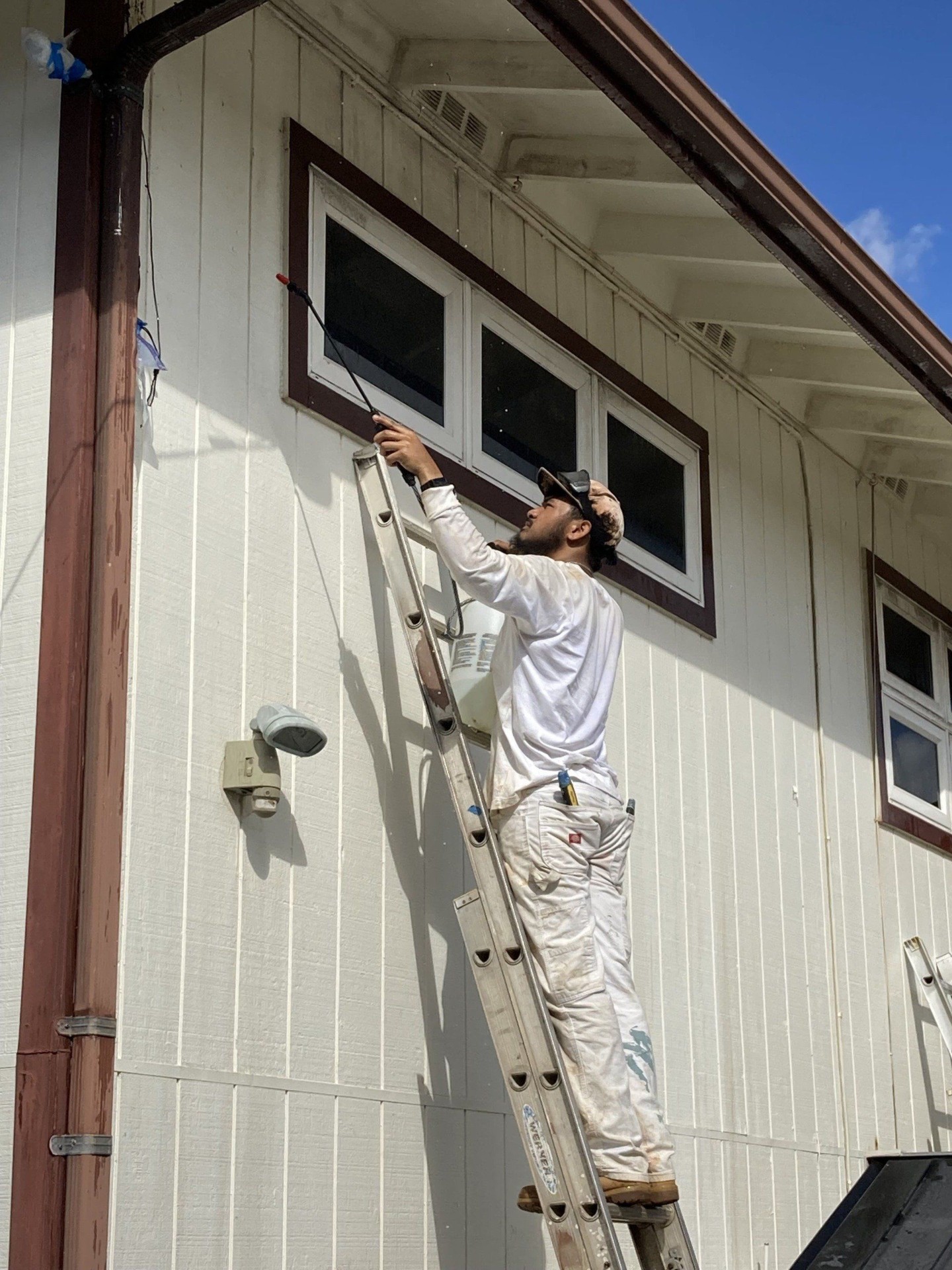Canencia painter spraying eaves on a residential exterior